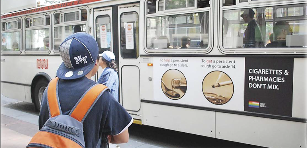 Youth on SF street looking at city bus board with anti tobacco messages. 